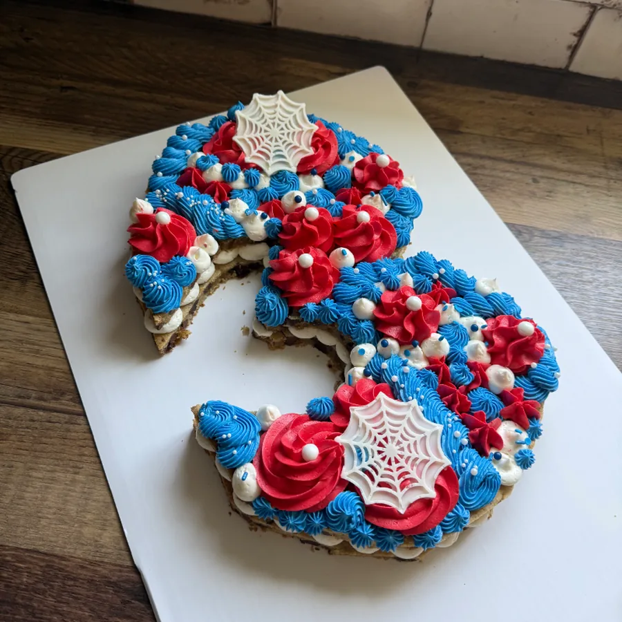 Number three cookie cake piped in red and blue with spider web details
