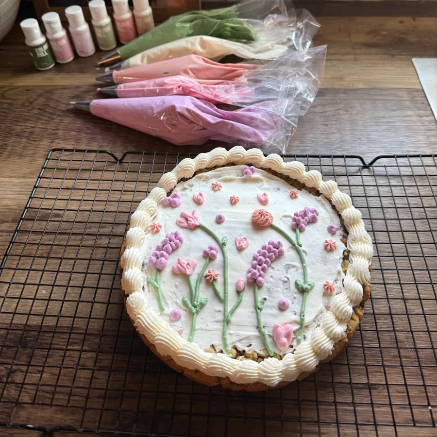 Round cake decorated with hand-piped buttercream wildflowers in soft pinks and greens